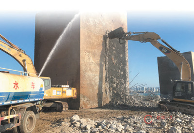 凤凰岛二期工程拆除施工期间,洒水车与挖掘机同步作业,降尘抑尘。   陈传忠摄